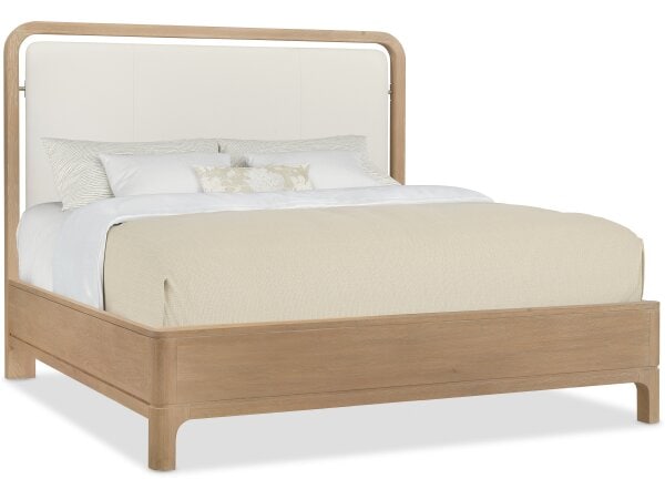 Natural wood bed frame with a beige upholstered headboard and neutral bedding, showcasing contemporary furniture design at Swann's Furniture & Design.