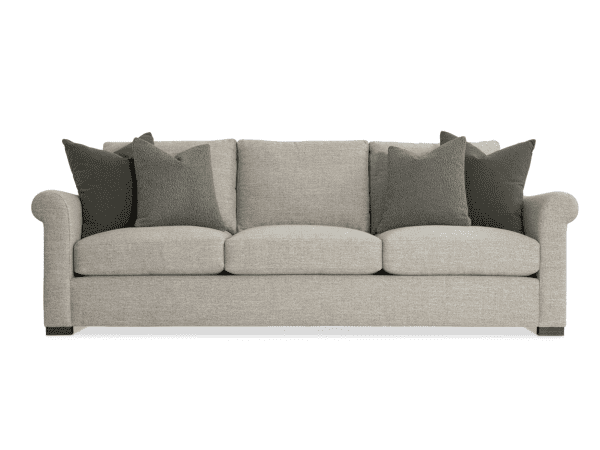 An inviting beige fabric sofa accented with dark pillows, ideal for living room comfort and style. This furniture piece showcases quality craftsmanship from Swann's Furniture & Design, serving Tyler, Texas.