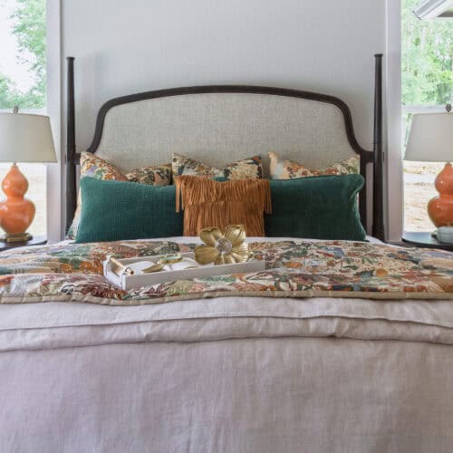 Luxurious Bedroom Featuring A Stylish Bed With Plush Pillows, A Floral Bedspread, And Matching Lamps On Bedside Tables, Creating A Cozy And Sophisticated Ambiance.