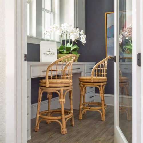 Bright Breakfast Nook Featuring Two Rattan Chairs And A White Built-In Desk With A Window View.