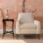 Elegant cream-colored armchair with textured fabric, paired with a dark wood side table holding a decorative bottle. Perfect for a stylish and comfortable living space.