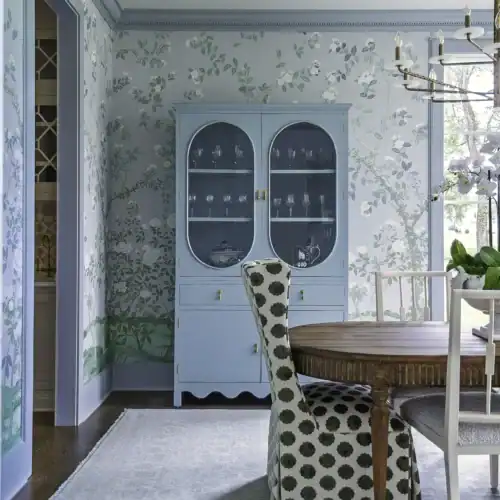 Elegant Blue China Cabinet With Glass Doors In A Bright Dining Room, Featuring A Round Wooden Table And Patterned Chairs, With A Chandelier Overhead.