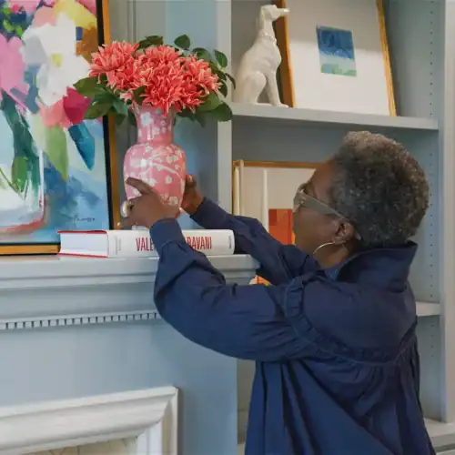 Woman Arranging Pink Flowers In A Decorative Vase On A Shelf At Swann'S Furniture Store In Tyler, Texas.
