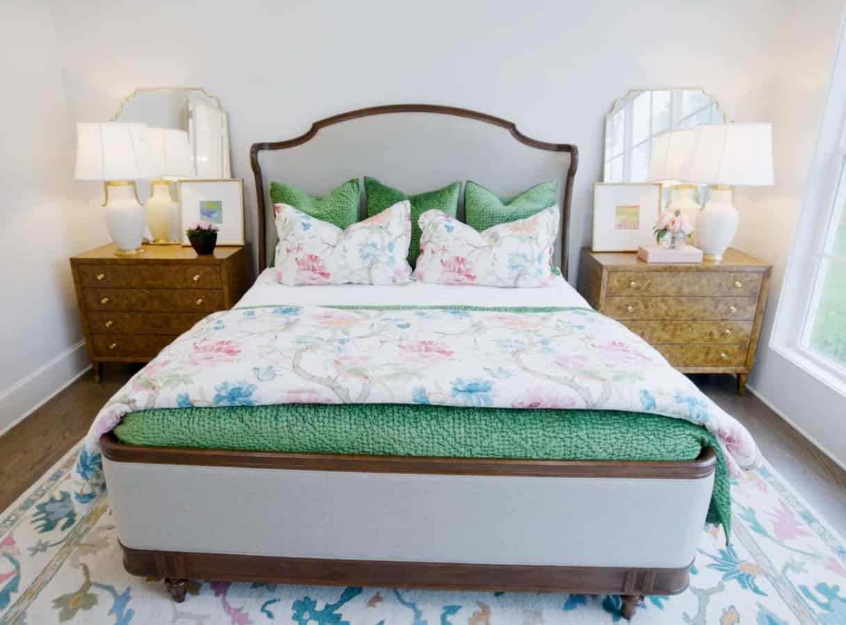 Beautiful Bedroom Featuring A Bed With Floral Bedding, Green Pillows, And Matching Nightstands With Lamps, In A Bright, Modern Setting.